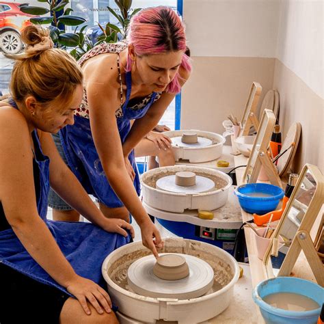 Zdjęcie przedstawiające dzieci pracujące z gliną przy ceramicznym kole.