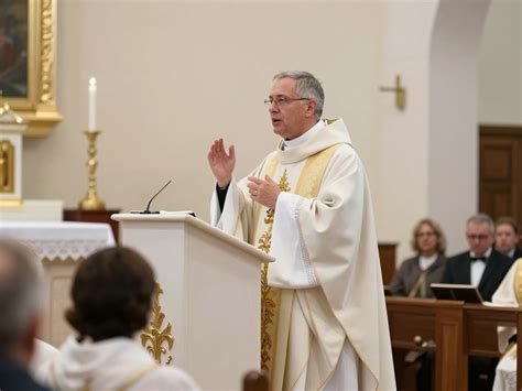 Zdjęcie młodego człowieka podczas ceremonii bierzmowania, gdzie biskup nakłada ręce i namaszcza go krzyżmem.