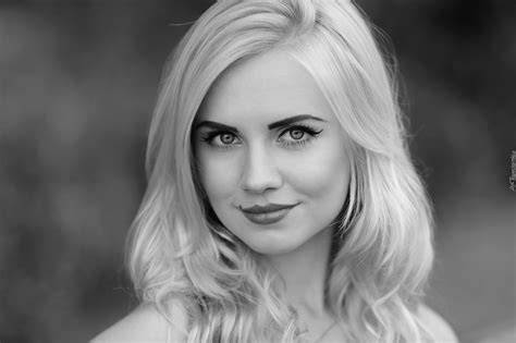 Portret uśmiechniętej kobiety w eleganckim stroju, symbolizujący profesjonalizm i pasję konsultanta ślubnego.