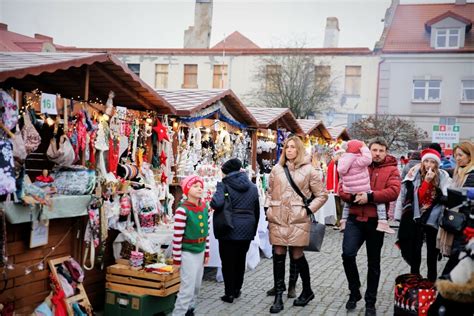 fotografie uczestników jarmarku świątecznego w Kobylinie, z elementami świątecznymi, placem i stoiskami