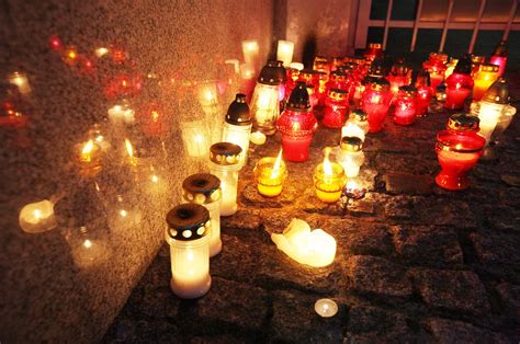 Zdjęcie współczesnego cmentarza w Dzień Zaduszny, z zapalonymi zniczami i kwiatami.