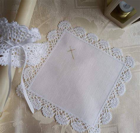 Krzyż, świeca chrzcielna i biała szata - przykładowe akcesoria liturgiczne wykorzystywane podczas sakramentu chrztu.