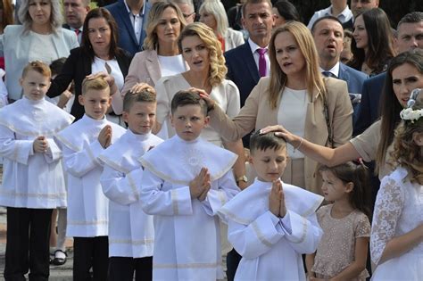 Zdjęcie dzieci ubranych w stroje komunijne przed kościołem
