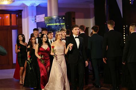 Zdjęcie grupy maturzystów w eleganckich strojach podczas studniówki.