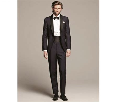 Zdjęcie przedstawiające elegancki męski garnitur balowy z dodatkami, takimi jak muszka i kapelusz.