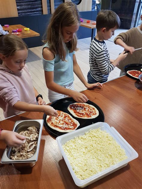 dzieci uczestniczące w warsztatach robienia pizzy na przyjęciu