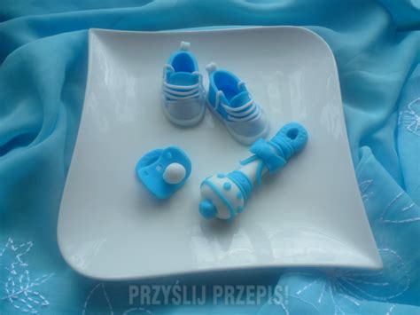 Przykładowe dekoracje z masy cukrowej na tort na chrzciny: buciki, smoczek, grzechotka.