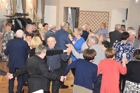 Zdjęcie pary tańczącej na parkiecie podczas imprezy andrzejkowej, z widocznymi efektami świetlnymi.
