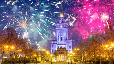 Grupa ludzi świętująca Sylwestra na placu w Uniejowie, z fajerwerkami w tle