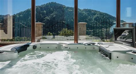 Grupa uśmiechniętych kobiet relaksująca się w jacuzzi na zewnątrz, z widokiem na las.