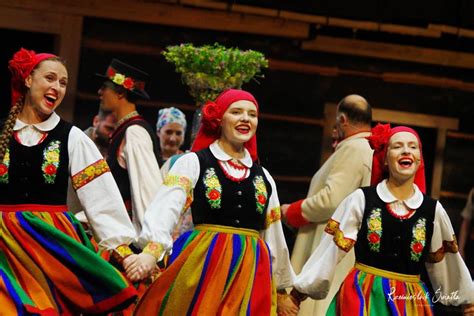 Grupa kobiet w ludowych strojach tańcząca na łące.