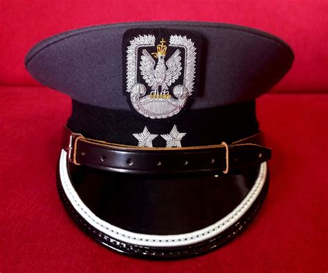 Zbliżenie na detale stroju policjantki: koronki, pasek, czapka z emblematem.