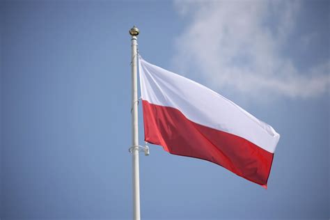 Ilustracja przedstawia widok na rozłożoną, lekko pofałdowaną, biało‑czerwoną flagę Polski.