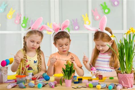 Ilustracja przedstawiająca dzieci malujące pisanki i bawiące się z zajączkiem.