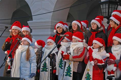 grupa ludzi śpiewających kolędy w sali ozdobionej świątecznie