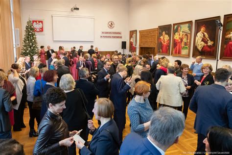 Uczestnicy spotkania wigilijnego siedzą przy stole, słuchając przemówienia.