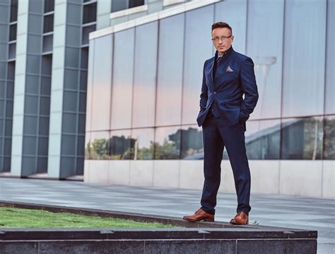 Mężczyzna w eleganckim garniturze z muchą i poszetką.