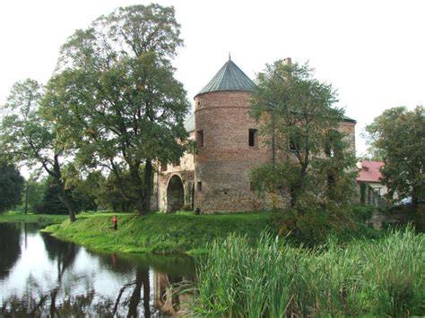 Widok ogólny zabytkowego dworu obronnego otoczonego fosą i stawami