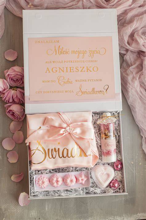 Ilustracja przedstawiająca zestaw prezentowy dla świadkowej: eleganckie pudełko z kosmetykami, biżuterią i winem.