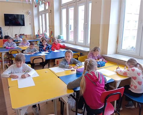 Dzieci pracujące przy stolikach, każde z nich przeprowadza eksperyment barwienia ryżu różnymi metodami.