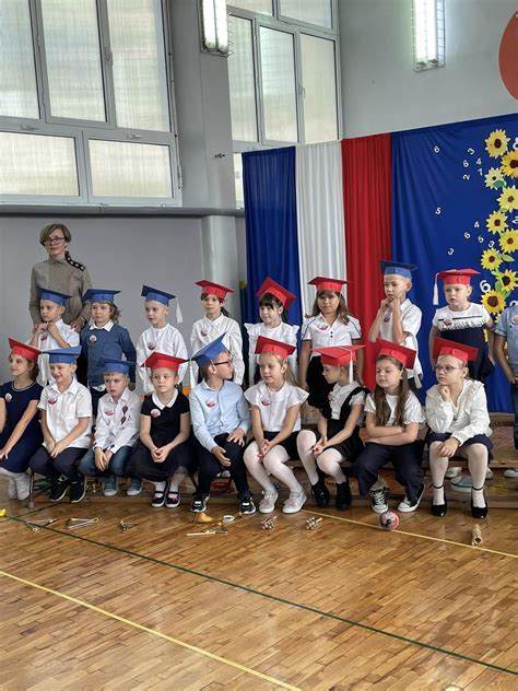 Zdjęcie uczniów otrzymujących dyplomy i nagrody podczas uroczystości szkolnej.