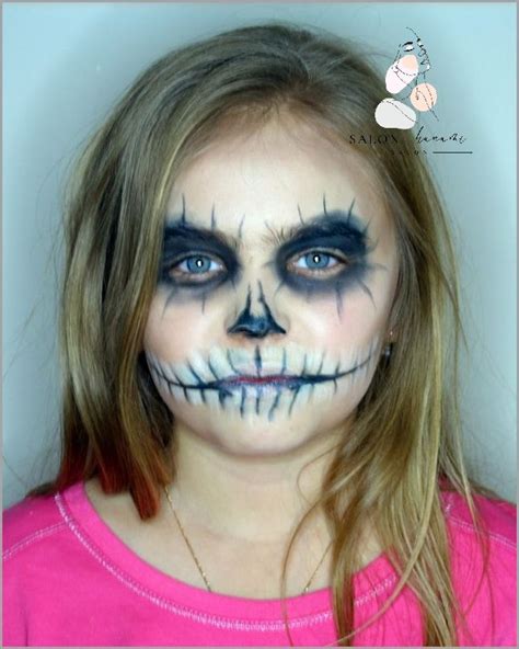 Kobieta malująca twarz dziecka na Halloween, tworząc fantazyjny wzór.