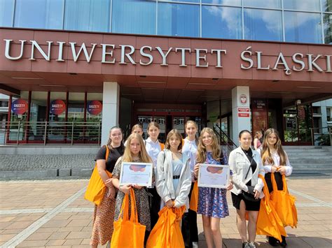 Grupa uczniów i nauczycieli pozująca przed nowym budynkiem szkoły, symbolizująca wspólny sukces.