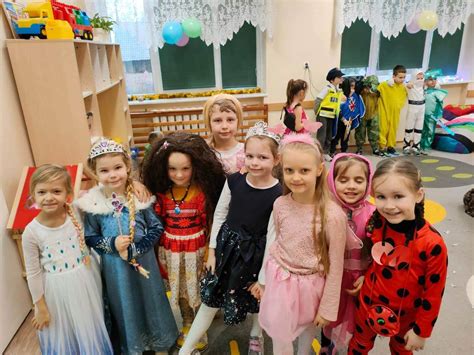Grupa przedszkolaków w różnorodnych strojach karnawałowych pozujących do wspólnego zdjęcia.