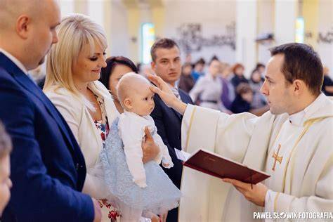zbliżenie na dłonie rodziców wykonujące znak krzyża na czole młodej pary
