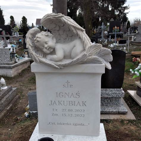 Zdjęcie przedstawiające nagrobek z aniołkiem i kwiatami, symbolizujący pamięć o zmarłym dziecku.