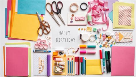 Zestawienie materiałów do tworzenia kartek urodzinowych: papiery do scrapbookingu, klej, nożyczki, kwiaty, perełki.