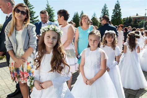 Zdjęcie dzieci w strojach komunijnych przed kościołem