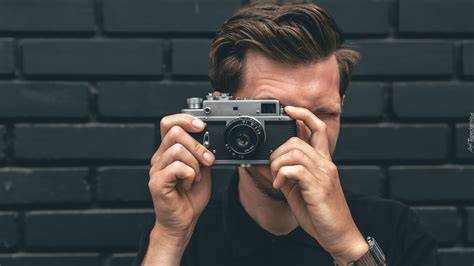 Portret Michała, fotografa ślubnego, z aparatem fotograficznym.